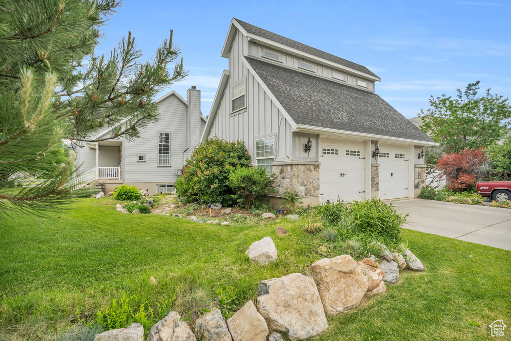 View of side of property featuring a garage and a lawn