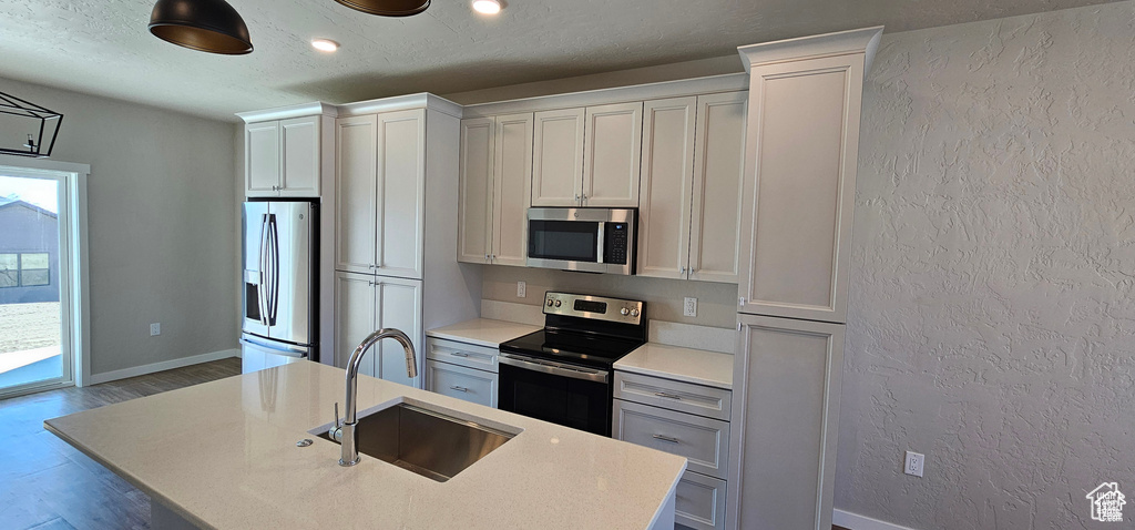 Kitchen featuring appliances with stainless steel finishes, sink, and an island with sink