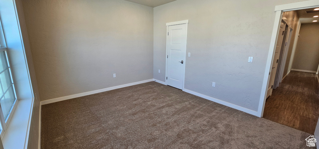 Unfurnished bedroom with dark colored carpet