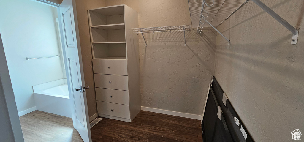 Walk in closet with hardwood / wood-style floors