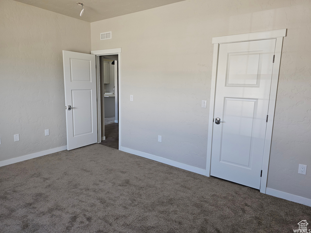 Unfurnished bedroom with dark carpet