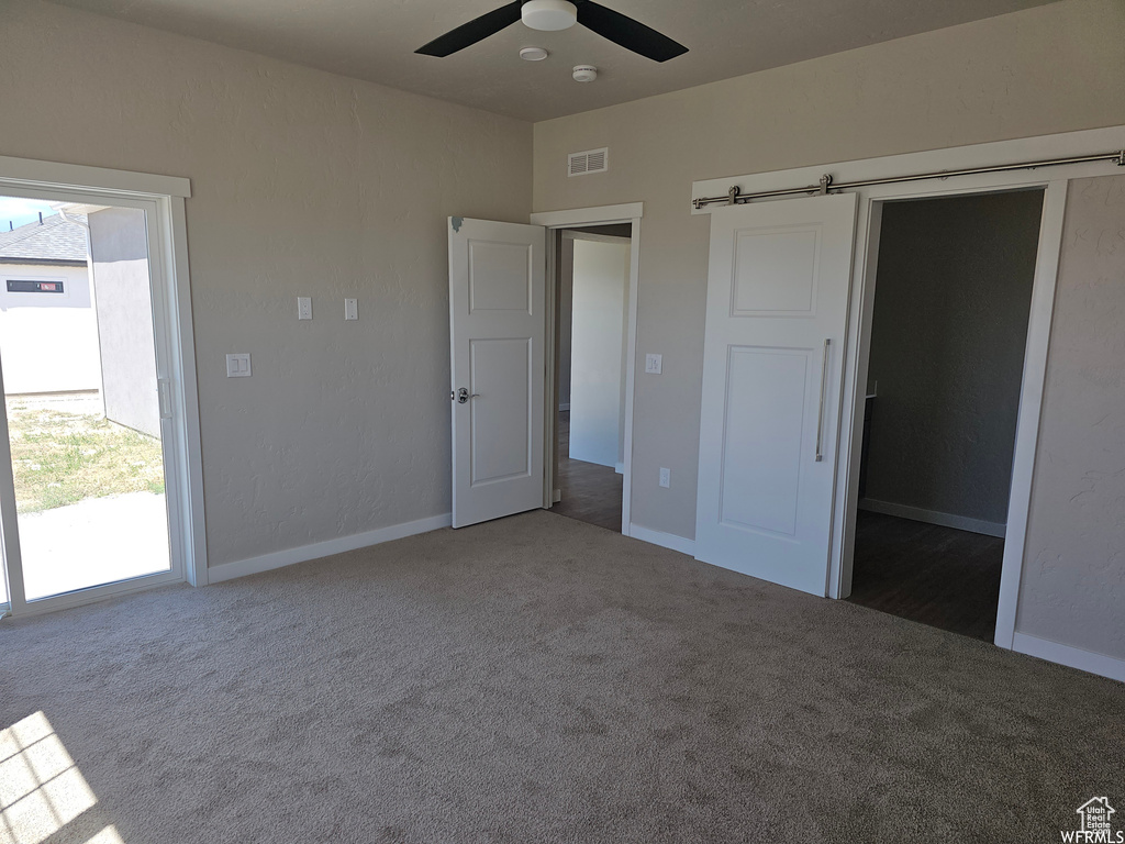 Unfurnished bedroom featuring a walk in closet, ceiling fan, and carpet floors