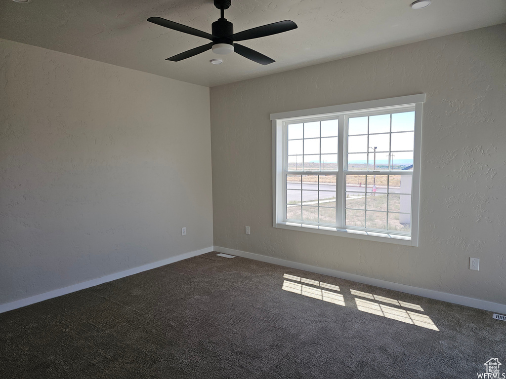 Empty room featuring ceiling fan and carpet floors