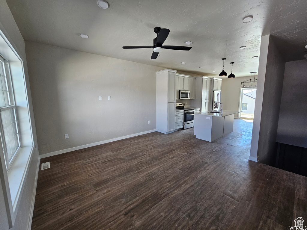 Unfurnished living room featuring dark hardwood / wood-style floors, ceiling fan, and sink