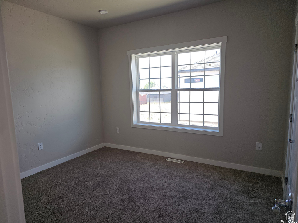 Unfurnished room featuring dark colored carpet