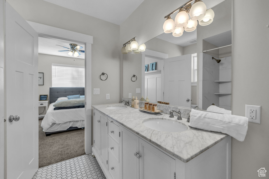 Bathroom with vanity with extensive cabinet space, dual sinks, ceiling fan, and tile floors