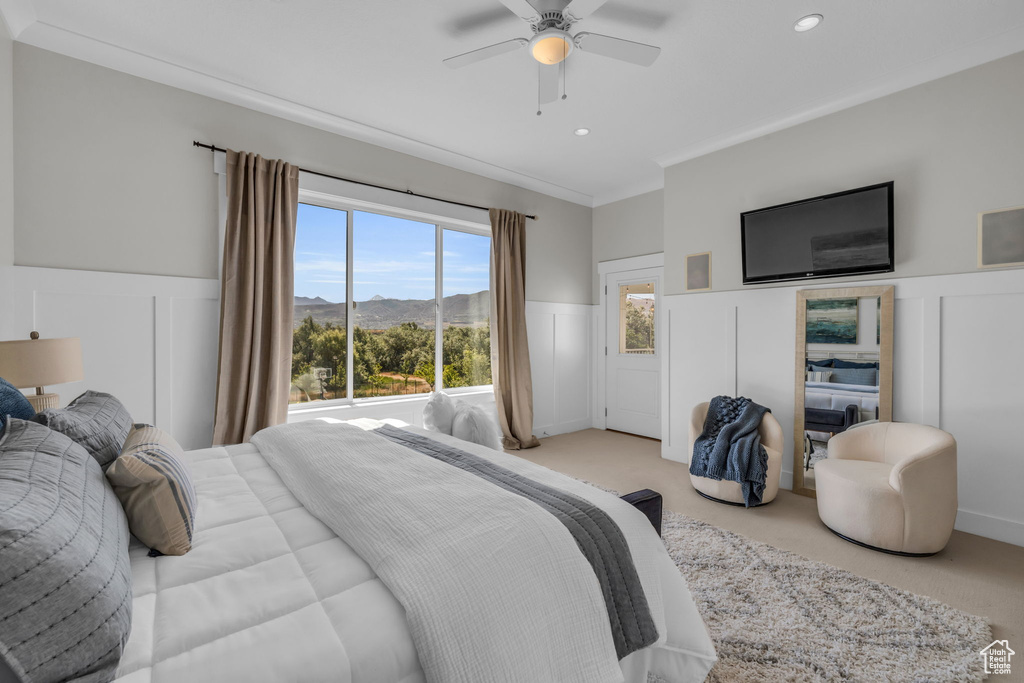 Bedroom featuring light carpet, ornamental molding, and ceiling fan