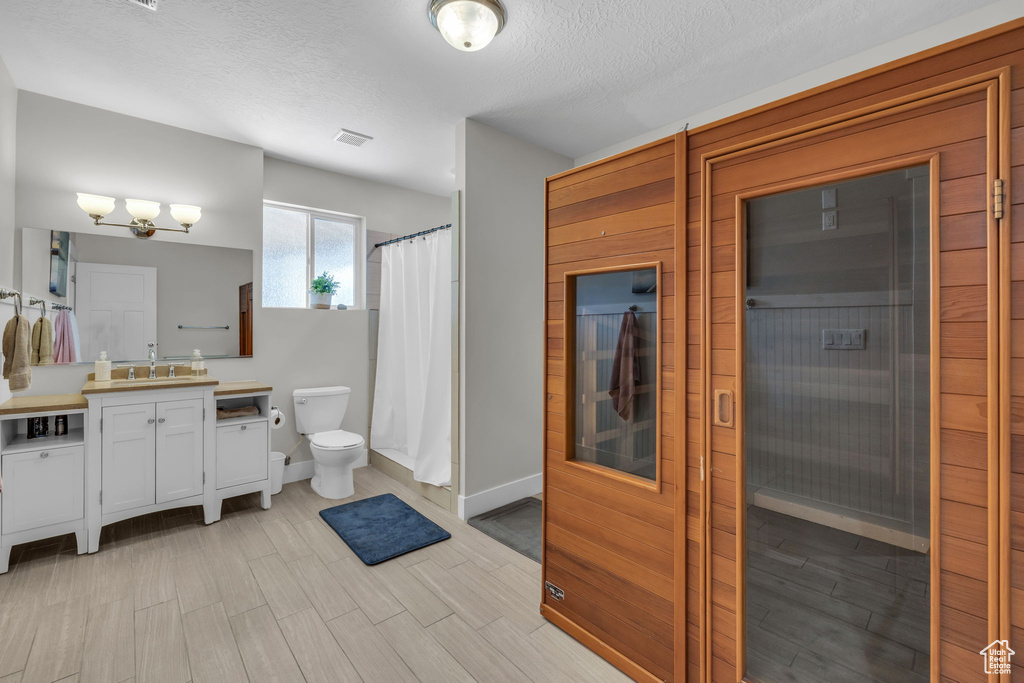 Bathroom featuring a textured ceiling, vanity, and toilet