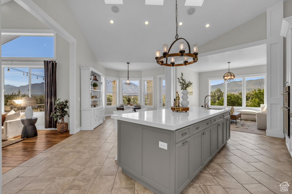 Kitchen with an island with sink, pendant lighting, and light tile floors