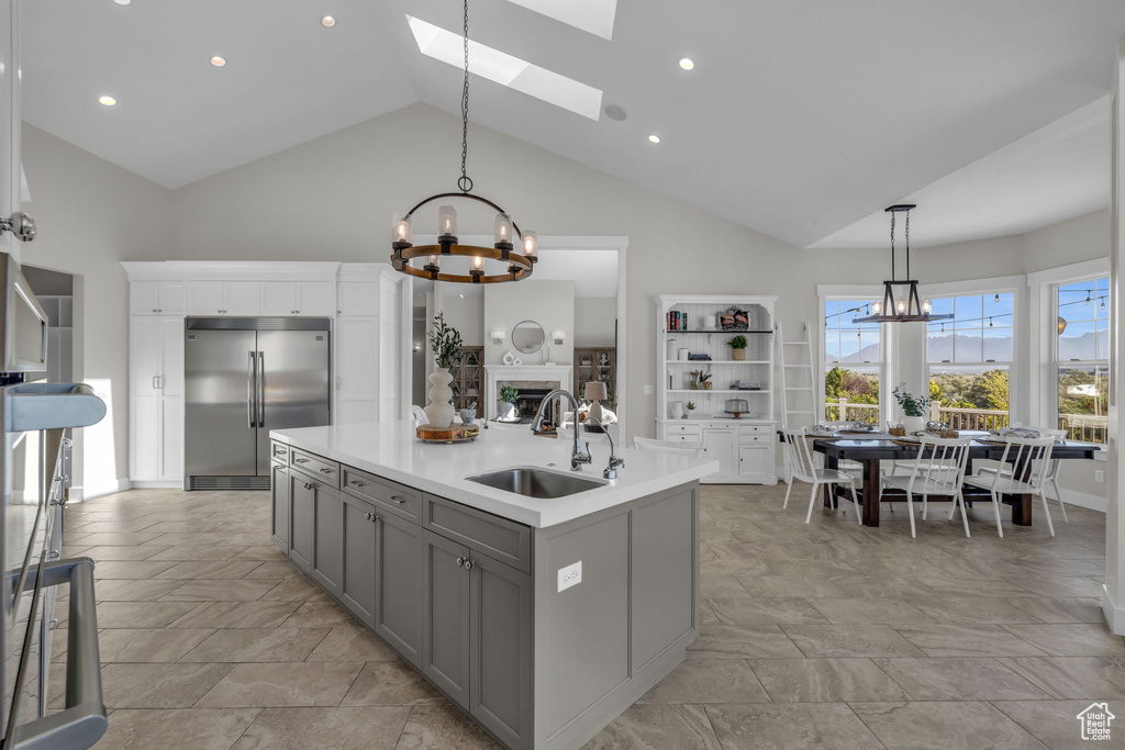 Kitchen with stainless steel built in fridge, light tile floors, high vaulted ceiling, sink, and a skylight