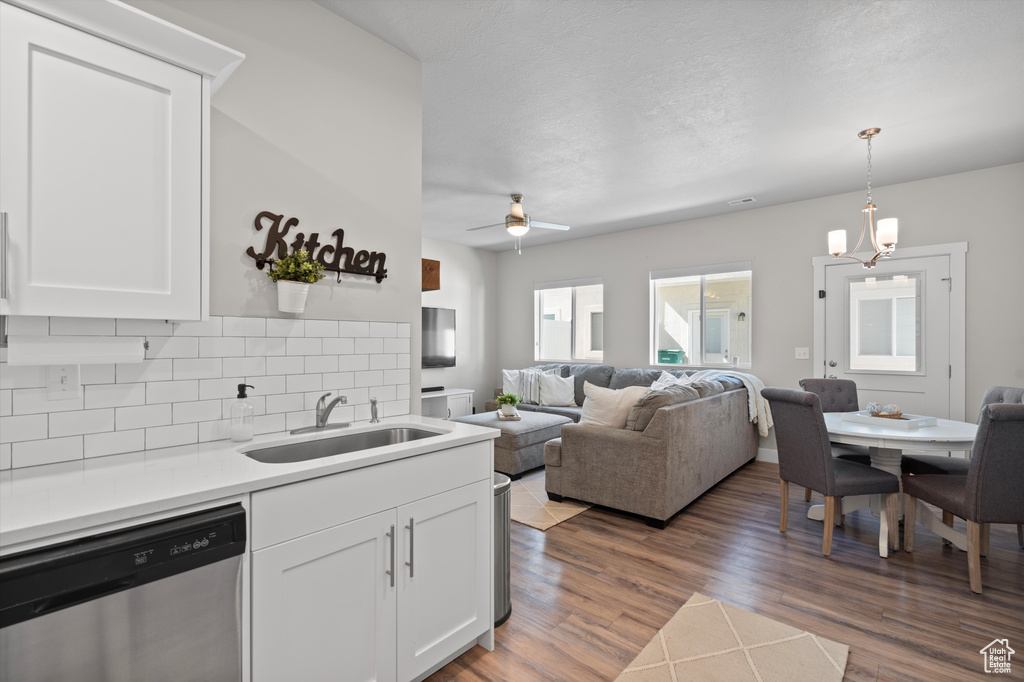 Kitchen with hardwood / wood-style flooring, tasteful backsplash, stainless steel dishwasher, white cabinets, and sink