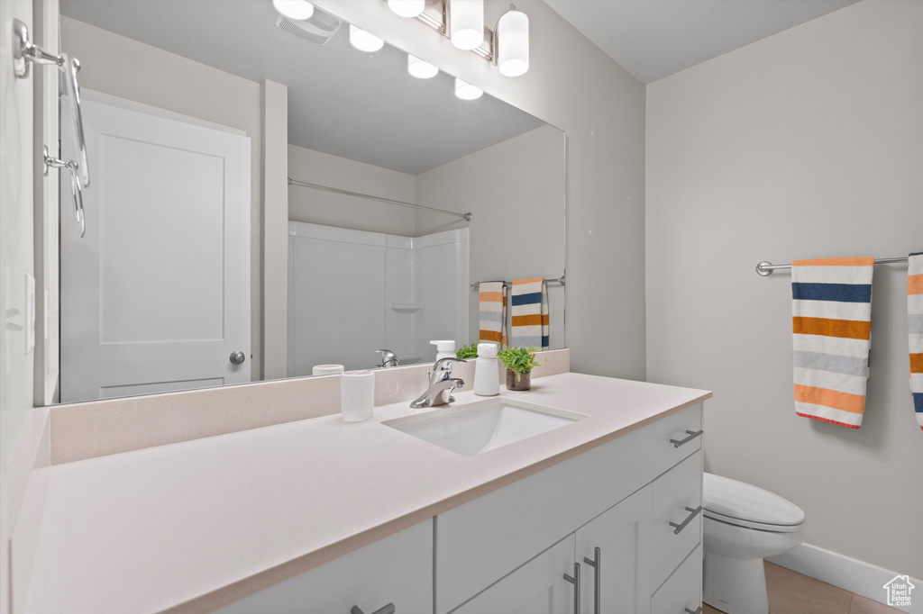 Bathroom featuring tile floors, toilet, and large vanity