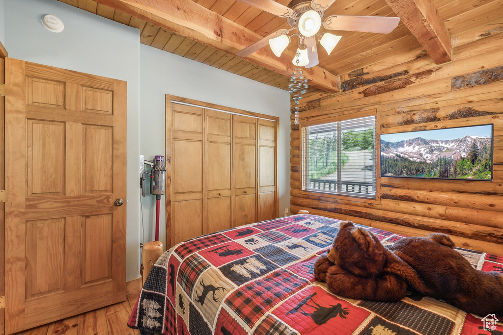 Bedroom featuring log walls, beamed ceiling, wood-type flooring, and wood ceiling