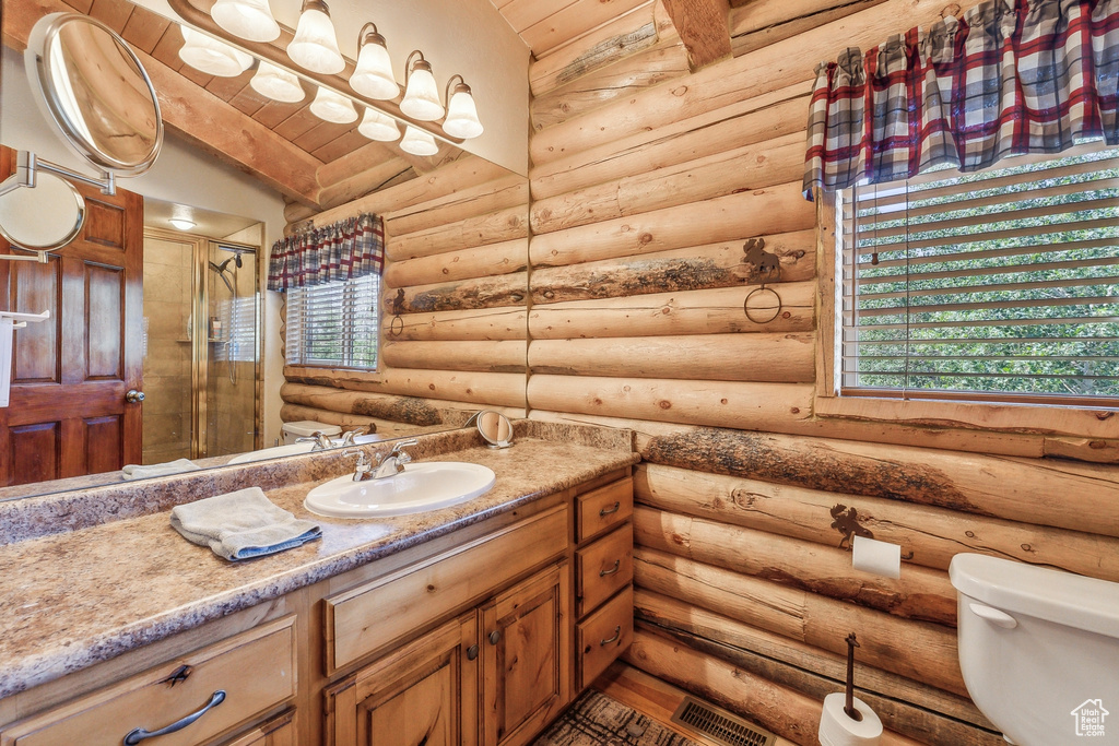 Bathroom with wooden ceiling, oversized vanity, log walls, and toilet