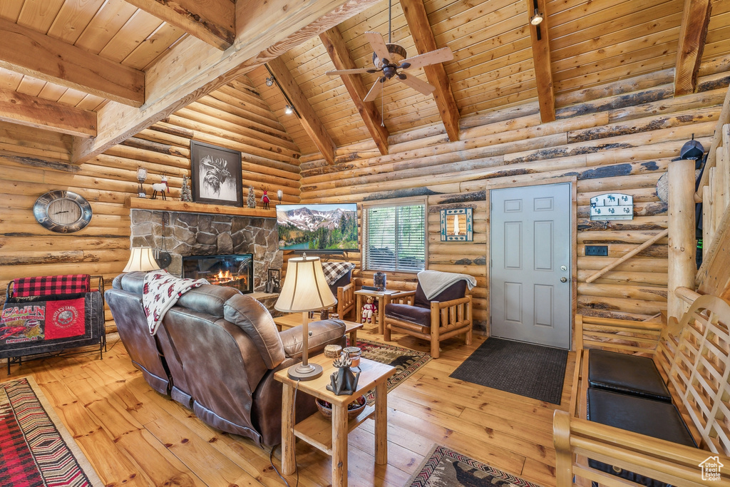 Living room with light hardwood / wood-style flooring, a fireplace, wood ceiling, lofted ceiling with beams, and log walls