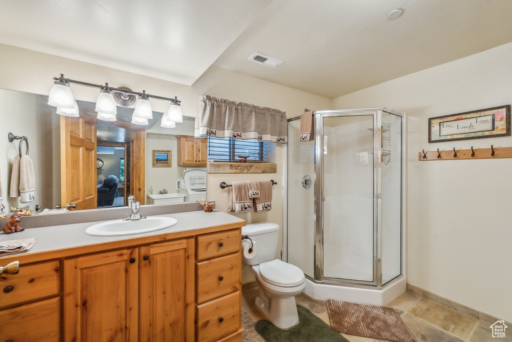 Bathroom with a shower with shower door, tile flooring, toilet, and vanity with extensive cabinet space