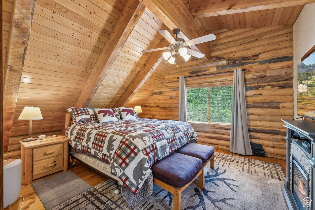 Bedroom featuring a stone fireplace, wooden ceiling, rustic walls, and wood-type flooring