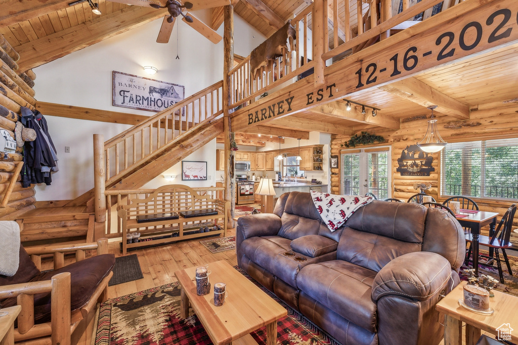 Living room with beamed ceiling, log walls, wooden ceiling, and rail lighting