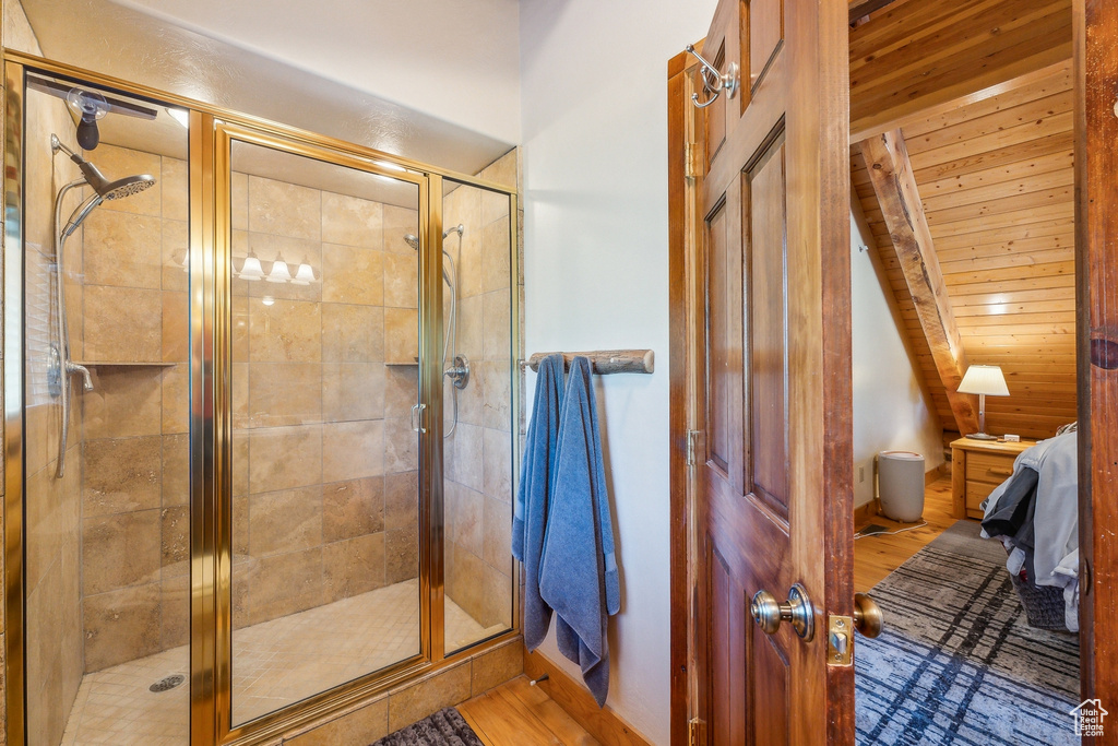 Bathroom with vaulted ceiling, wooden walls, wooden ceiling, hardwood / wood-style floors, and walk in shower