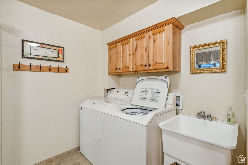 Washroom featuring cabinets, washer and clothes dryer, hookup for a washing machine, sink, and light tile floors