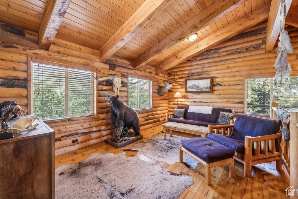 Living room with wooden ceiling, hardwood / wood-style flooring, rustic walls, and vaulted ceiling with beams