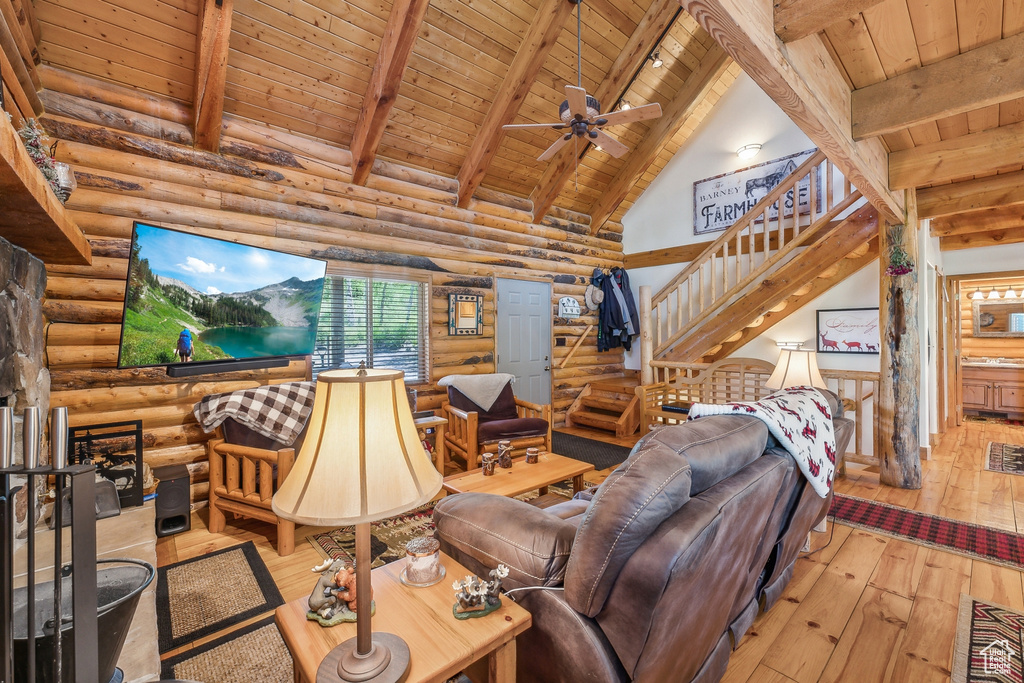 Living room featuring light hardwood / wood-style floors, ceiling fan, wooden ceiling, beamed ceiling, and log walls