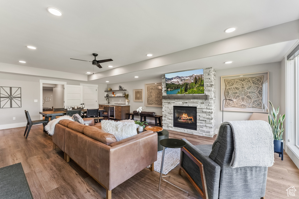 Living room with a wealth of natural light, a fireplace, light wood-type flooring, and ceiling fan