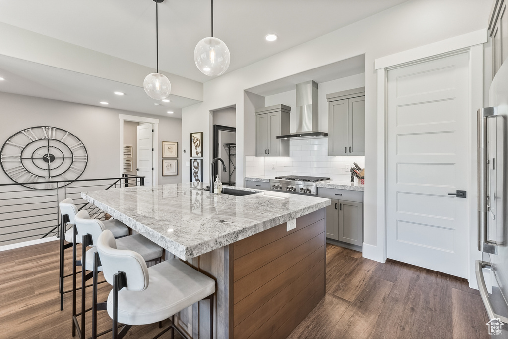 Kitchen featuring wall chimney range hood, sink, dark hardwood / wood-style flooring, and tasteful backsplash