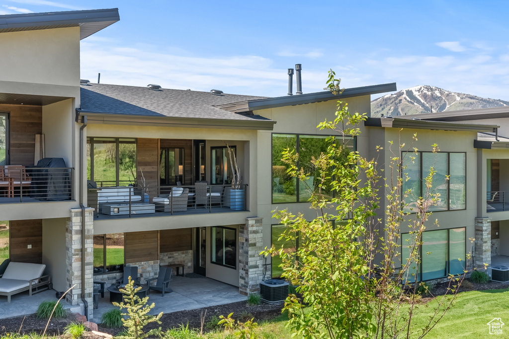 Rear view of house featuring a mountain view, a patio area, a balcony, and central air condition unit