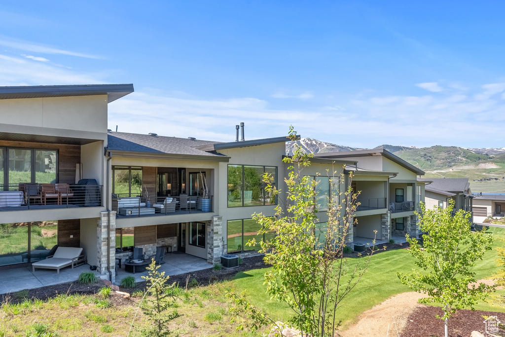 Back of property featuring a yard, a patio area, and a balcony