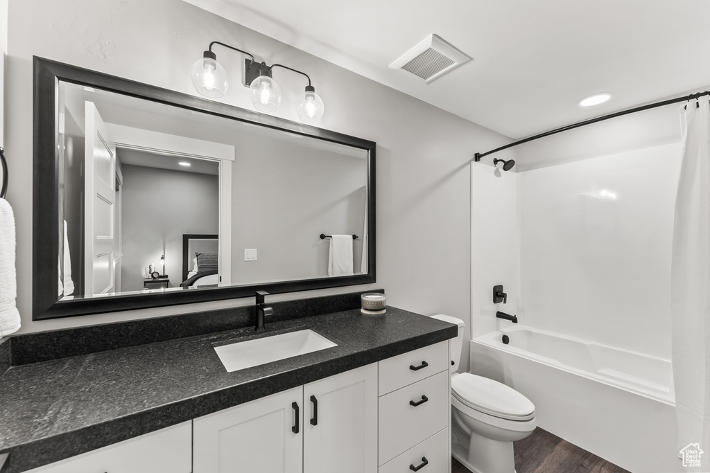 Full bathroom featuring oversized vanity, shower / bath combo, hardwood / wood-style flooring, and toilet