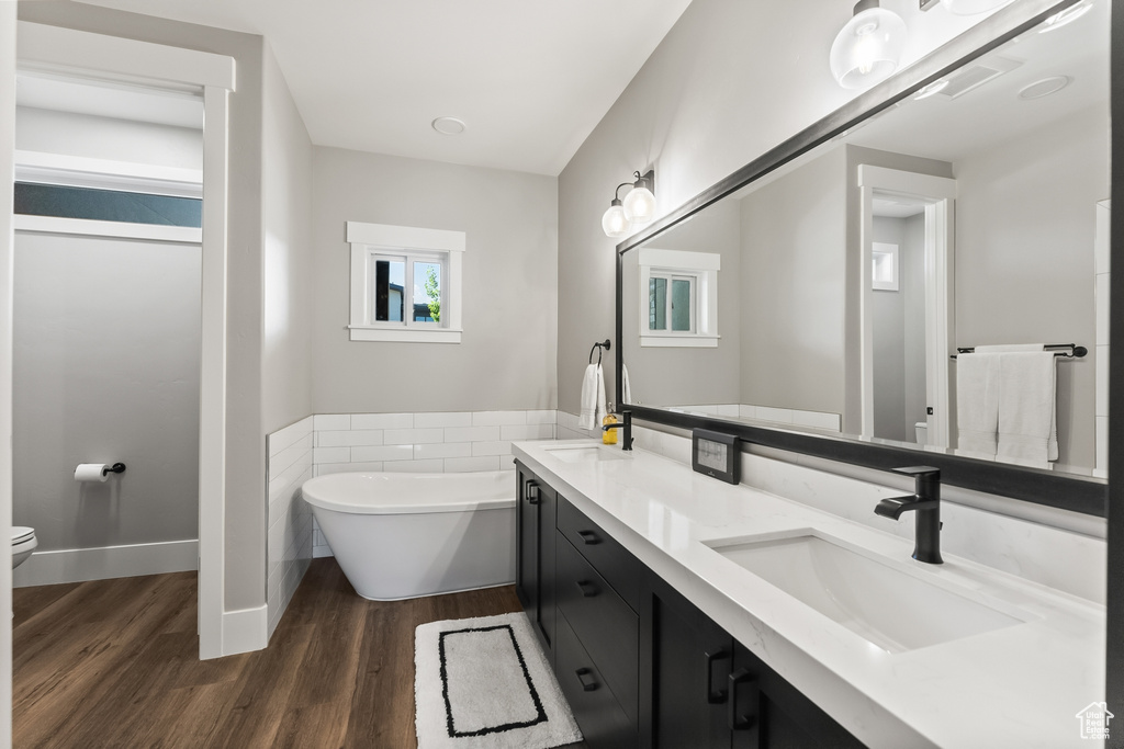 Bathroom featuring double sink vanity, hardwood / wood-style flooring, toilet, and a bathing tub