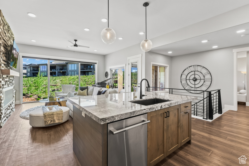 Kitchen featuring dark hardwood / wood-style flooring, a kitchen island with sink, stainless steel dishwasher, sink, and pendant lighting