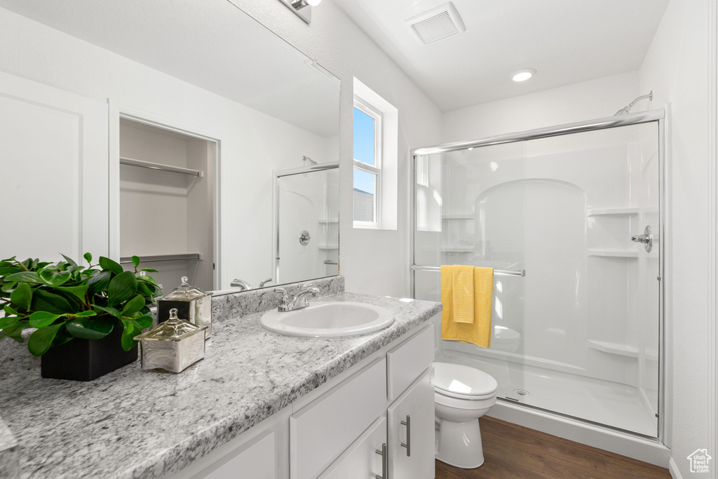 Bathroom with a shower with door, vanity, wood-type flooring, and toilet