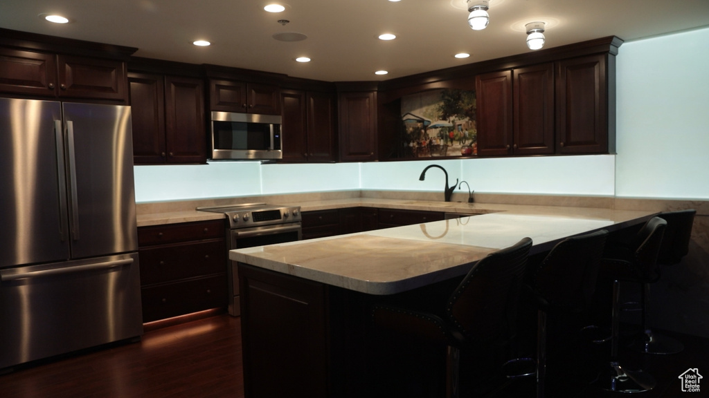 Kitchen with sink, dark wood-type flooring, dark brown cabinets, and stainless steel appliances