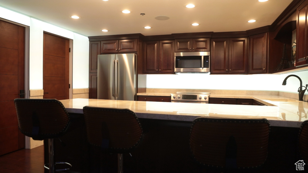 Kitchen featuring stainless steel appliances, sink, dark hardwood / wood-style floors, and dark brown cabinetry