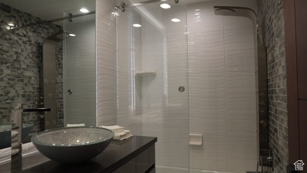 Bathroom featuring tiled shower and vanity