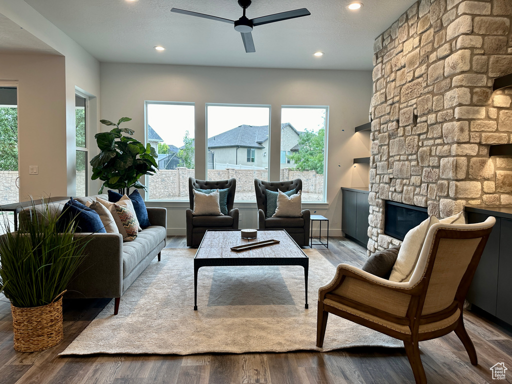 Living room featuring ceiling fan, a fireplace, and light hardwood / wood-style floors