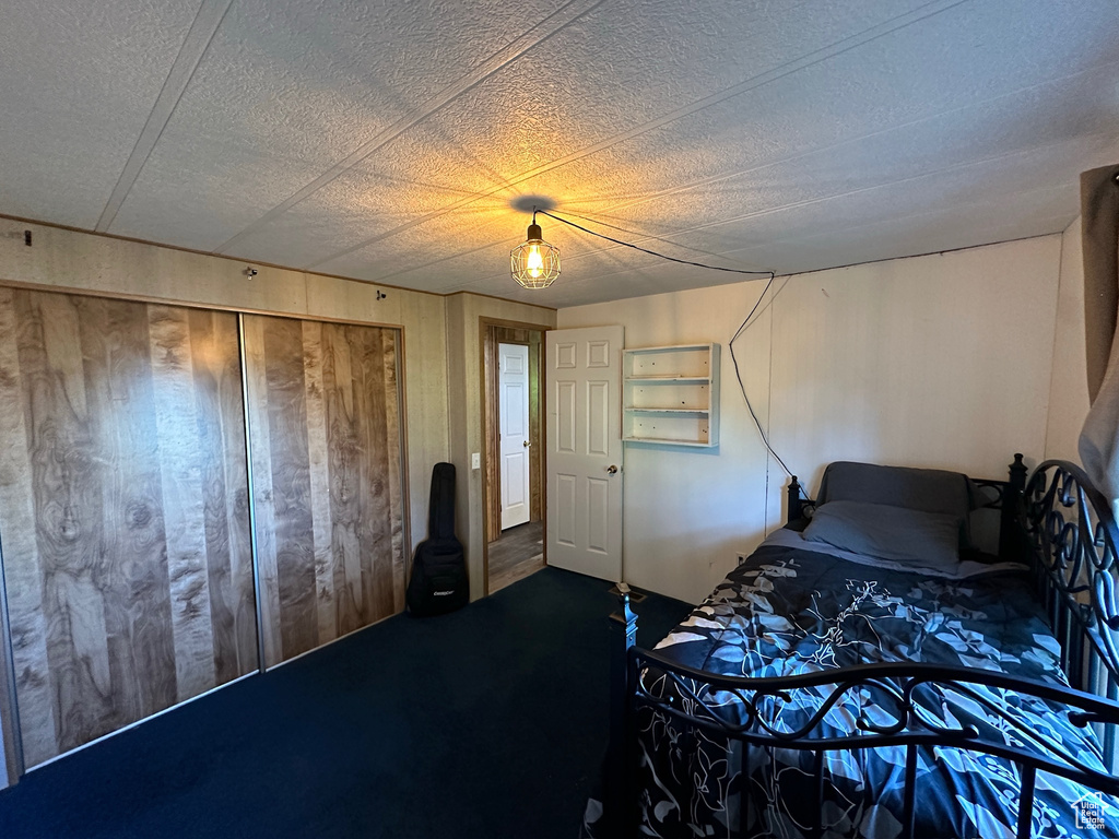 Bedroom with a textured ceiling, a closet, and dark colored carpet