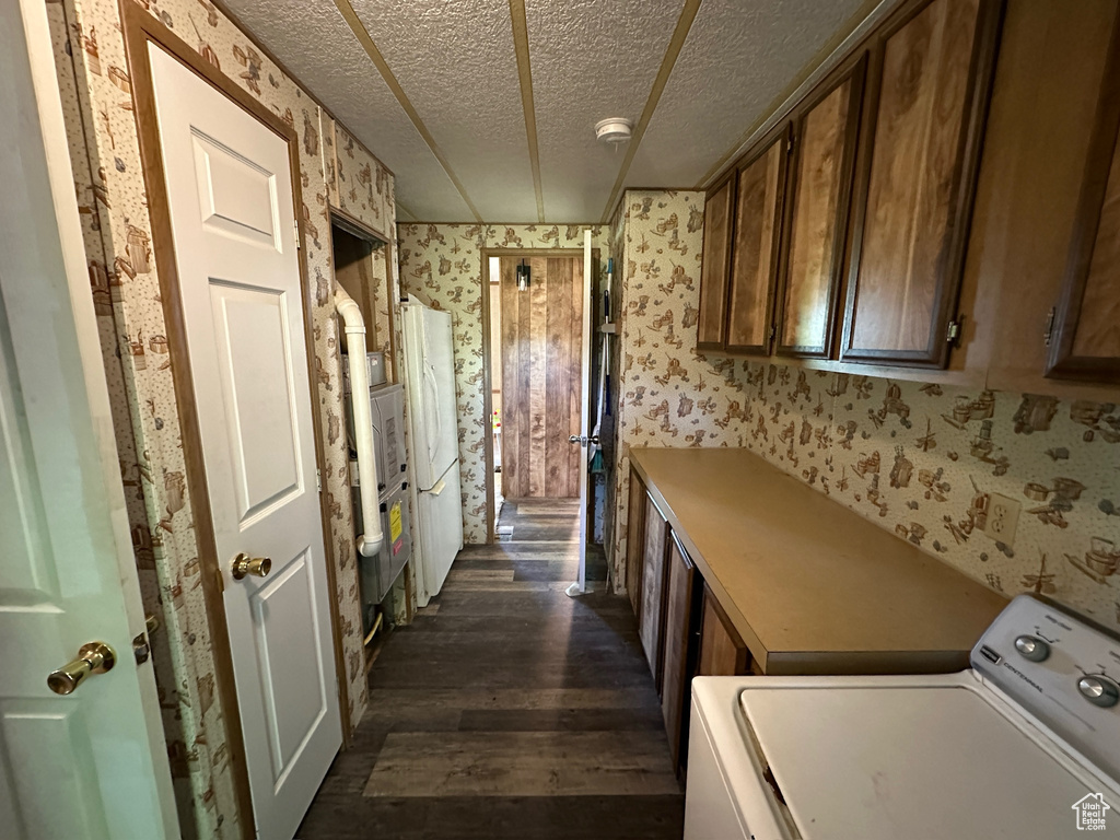 Clothes washing area featuring dark wood-type flooring, a textured ceiling, and washer / clothes dryer