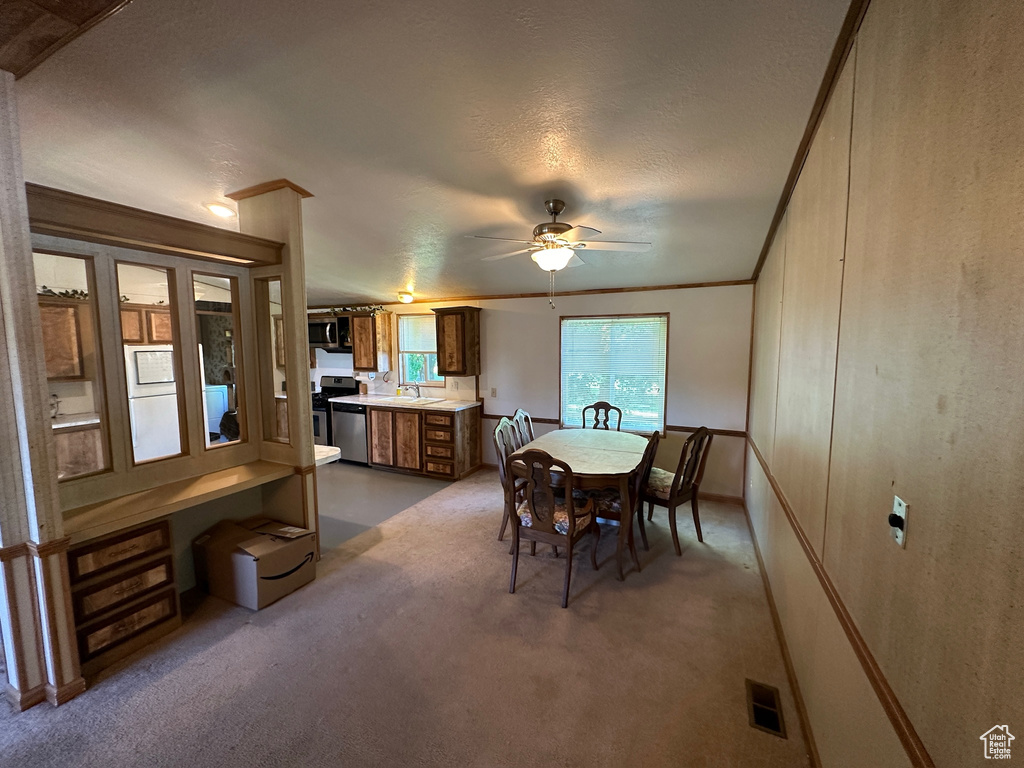 Dining space with ceiling fan, carpet flooring, and sink