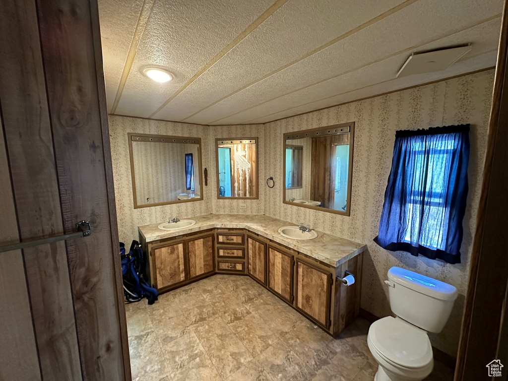 Bathroom with a textured ceiling, vanity, toilet, and tile floors