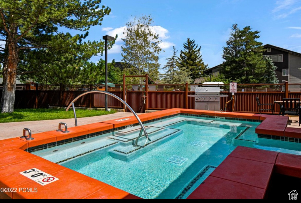 View of pool featuring a grill, a hot tub, and a wooden deck