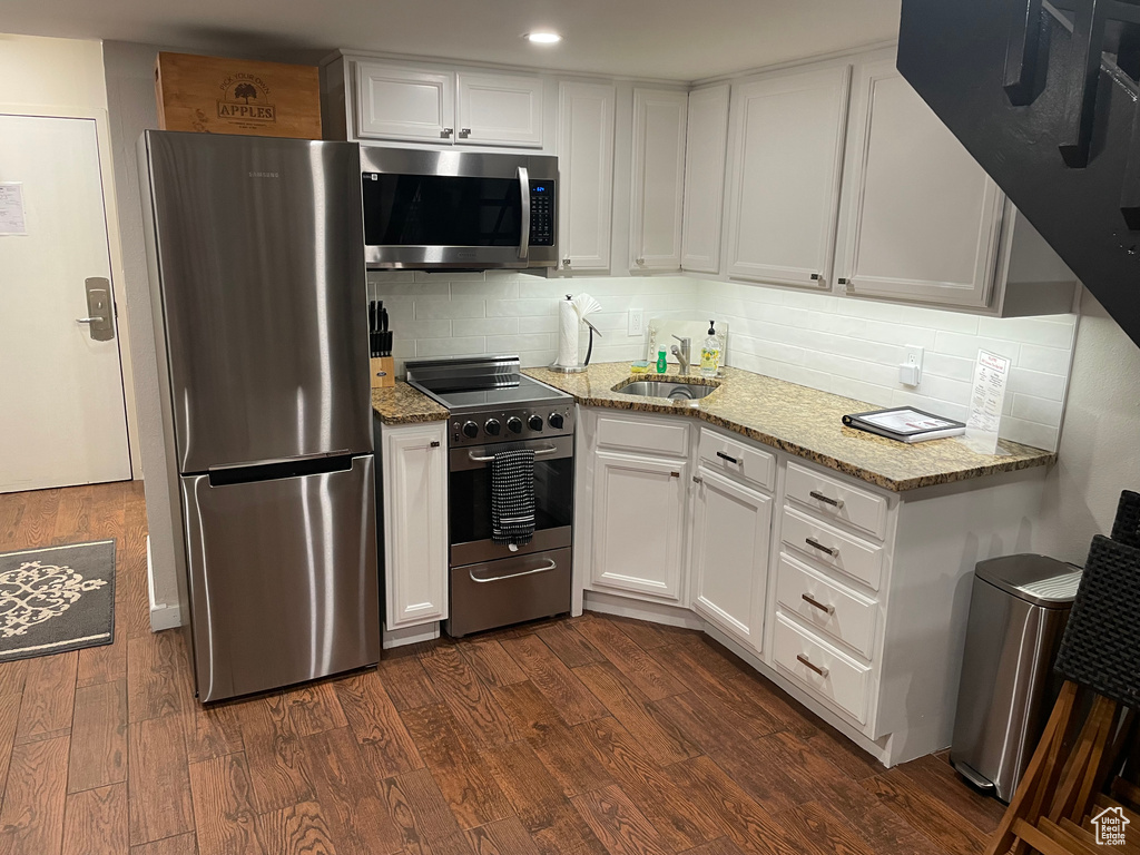 Kitchen featuring white cabinetry, appliances with stainless steel finishes, dark hardwood / wood-style flooring, and backsplash