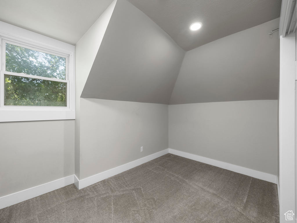 Bonus room with vaulted ceiling and dark carpet