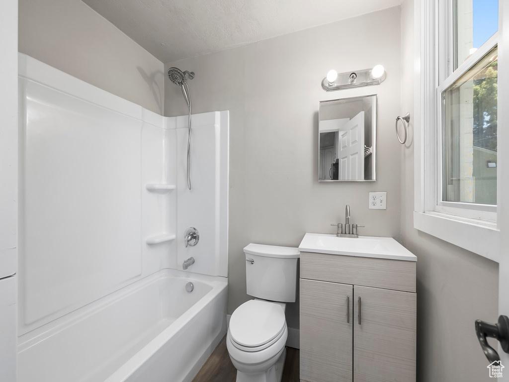 Full bathroom with vanity with extensive cabinet space, a textured ceiling, toilet, and bathing tub / shower combination