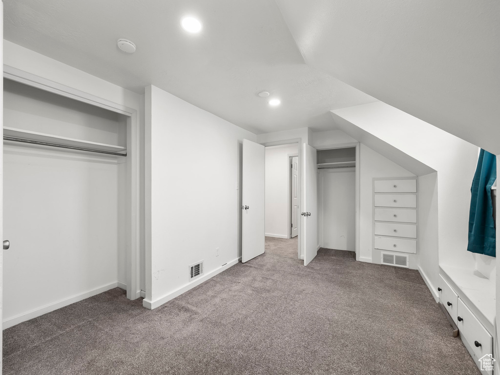 Unfurnished bedroom with lofted ceiling and dark colored carpet