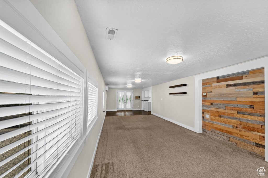 Interior space with dark colored carpet and a textured ceiling