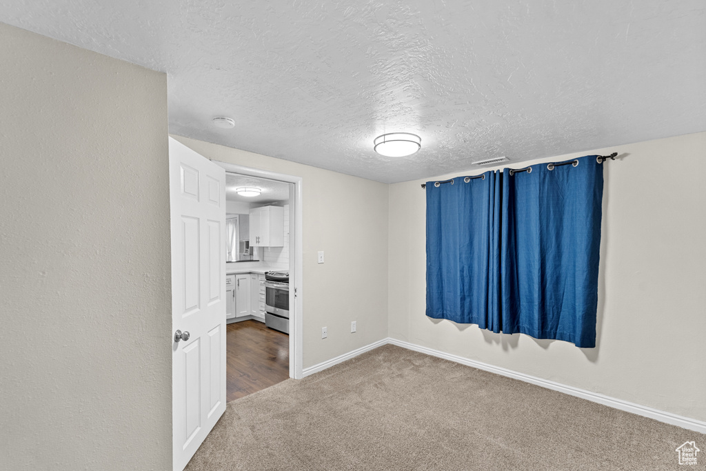 Carpeted empty room with a textured ceiling