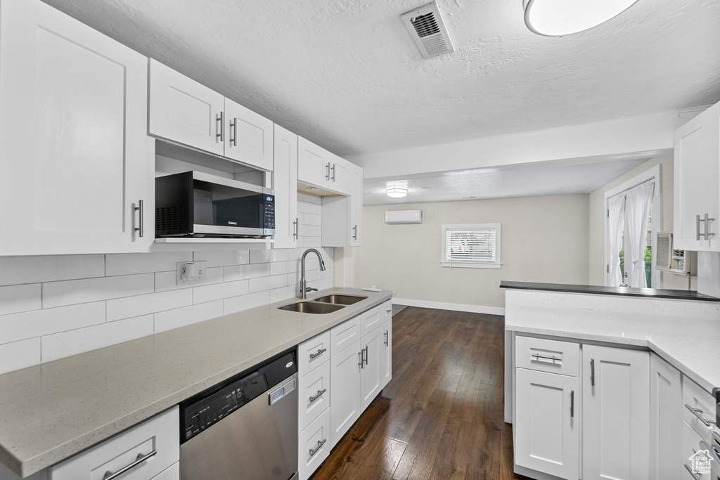 Kitchen featuring tasteful backsplash, dark hardwood / wood-style flooring, sink, white cabinets, and appliances with stainless steel finishes